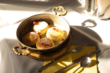 cottage cheese pancakes with pomegranate seeds in a frying pan on the table