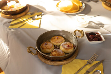 A pan with cottage cheese pancakes with pomegranate and orange slices in sunlight