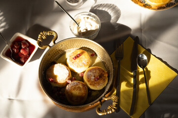 ruddy cottage cheese pancakes with pomegranate seeds in a frying pan in the sunlight