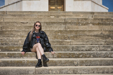 Young, beautiful, blonde woman, with leather jacket, snake miniskirt, boots and sunglasses, posing...