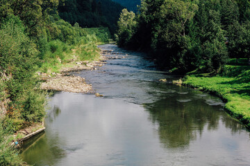 Serene river flows through a lush green landscape in the afternoon light