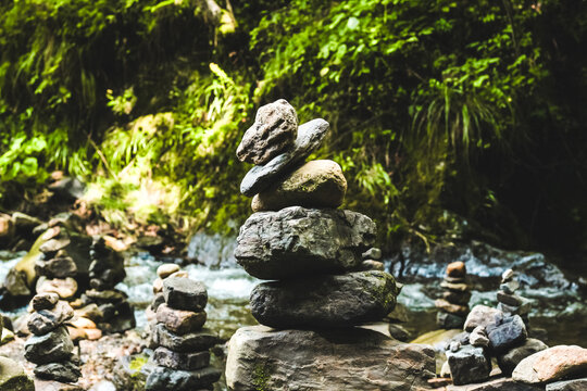 Balance and tranquility found in stacked stones near a flowing stream in a lush forest setting