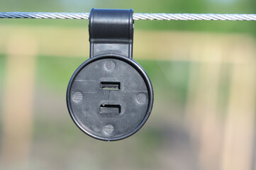 
Close-up of a plastic shade net attached to a metal cable. Blurred background