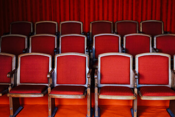 Rows of red upholstered chairs arranged in a theater setting for performance attendees