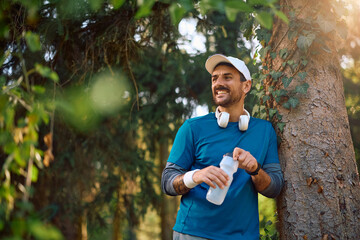 Happy sportsman having water break during outdoor workout.