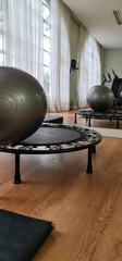 A workout room bathed in soft light filtering through the curtains, featuring a trampoline and an...