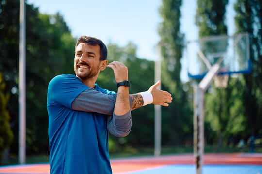 Happy athletic man doing stretching exercises during sports training outdoors.