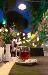Traditional Turkish tea served in a glass with sugar cubes on a plate in a cozy café setting