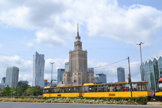 Iconic Palace of Culture and Science Dominating the Skyline of Warsaw, Poland, with Modern Skyscrapers and a Bright Yellow Tram on a Sunny Day