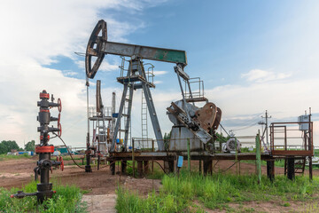 Oil production at the field using two rocking machines. In the background is a drilling rig and...