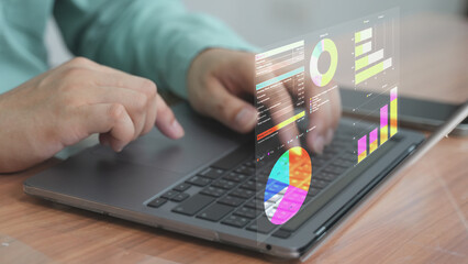 A business graph and data chart projected from laptop screen with finger interaction, showing business intelligence or financial data.
