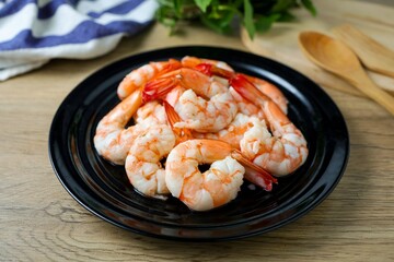 Boiled shrimp in black  ceramic plate on wooden background , 