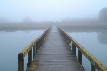 Long wooden footbridge extending into a foggy landscape over calm water in early morning light, Moving out to the end of a long wooden footbridge on a very foggy morning