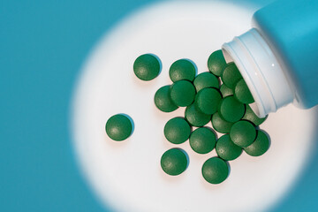 Close up of green medical pills  of iron on white background with blue shadows