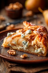 A freshly baked tart featuring a filling of sliced pears and blue cheese rests on a rustic plate. This cozy autumn dish is garnished with walnuts, perfect for a warm gathering