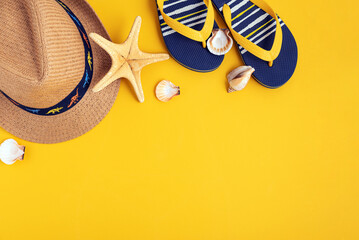 Kids beach summer frame from sea shells, straw hat, sandals on yellow background. Top view. Copy space