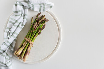Fresh asparagus tied bundle on white table. Top view