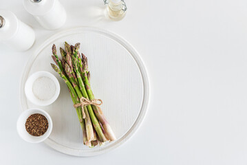 Fresh asparagus shoots with spices on white table. Top view