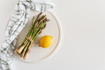 Fresh asparagus shoots with lemon on white table. Top view
