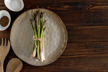 Asparagus spears, salt, pepper, oil and wooden utensils on rustic table. Top view
