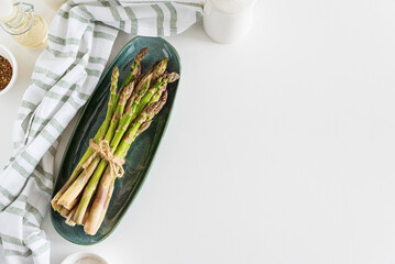 Fresh asparagus shoots with spices on white table. Top view