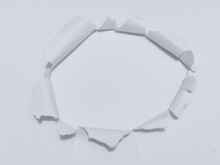 Torn hole on white paper on smooth white background. Sheet of white torn paper with blank space for...