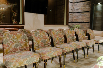 Upholstered chairs with an earthy leaf design on dark wood legs with brass detailing, arranged on a...