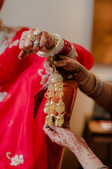 A bride's hands adorned with henna hold a golden traditional ornament, preparing for a wedding, and...