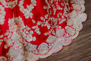 Elegant red fabric with intricate silver floral embroidery and scalloped edge detailing, showcasing...
