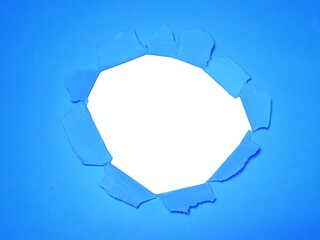 Torn hole on blue paper on smooth white background. Sheet of blue torn paper with blank space for...