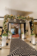 Elegant entrance with floral archway, mirror balls, and geometric carpet, creating a glamorous event space.