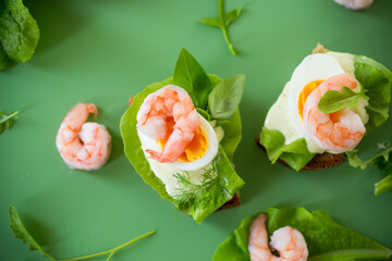 Appetizing breakfast with shrimp, egg and greens on top