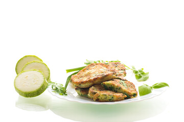 breakfast of zucchini pancakes with green onions in a plate on a white background
