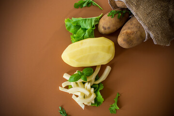 Nutritious potatoes whole, peeled and sliced on a brown background