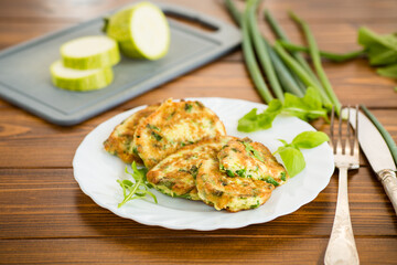 appetizing zucchini pancakes with green onions in a plate on a wooden table