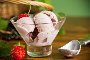 Blackcurrant ice cream with strawberries on green background