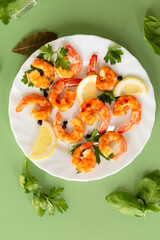 Golden fried shrimps with spices and fresh lemon in a plate isolated on green