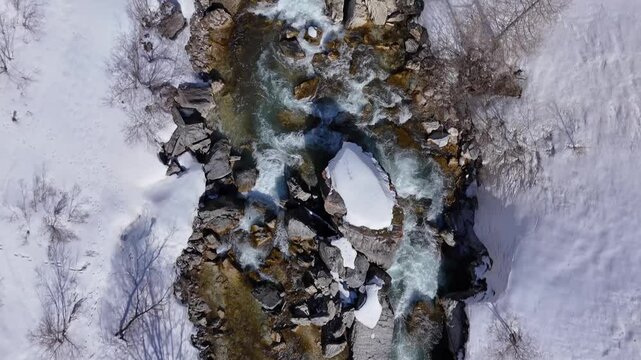Vue a&eacute;rienne d'une rivi&egrave;re bord&eacute;e de neige en montagne