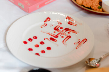 Plate Art: Red sauce patterns on white, showcasing culinary creativity. Abstract dots and lines for a unique food presentation. A playful dessert design.