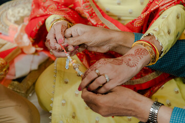 Hands intertwined during a cultural ceremony, adorned with henna and traditional jewelry,...