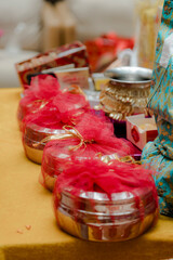 Decorated gift containers, each adorned with red netting and gold ribbon, sit in a line on a gold surface, conveying celebration and thoughtful presentation.