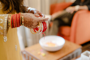 Elegant hands adorned with henna and vibrant bangles, engaged in a delicate ritual. Symbolizing tradition, beauty, and cultural richness.