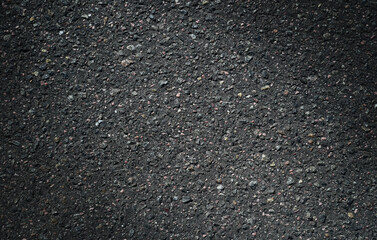 Texture of dark, grainy asphalt with uneven texture. Rough, abstract background.