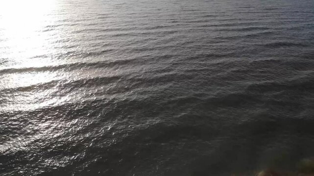 Aerial view of gentle ocean waves reflecting sunlight along the coastline of Qeshm Island, Iran