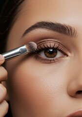 Naklejka premium Close-up of a Woman Applying Eyeshadow with a Brush Achieving a Natural, Effortless Look