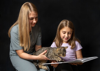 Happy mother and daughter bonding over their adorable tabby kitten. Emotional and tender family...