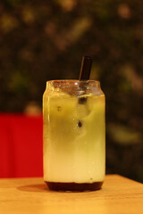 Matcha with strawberry puree, milk and ice. Refreshing sweet drink in a glass with a straw. Close-up of matcha. Drink on a table in a cafe or restaurant. Glass of strawberry green tea