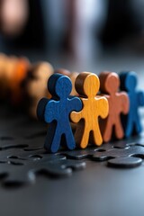 Colorful wooden figures connect on jigsaw puzzle pieces to illustrate teamwork and inclusivity in business practices