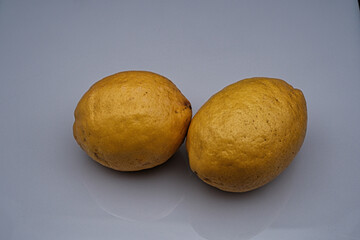 Pair of yellow lemons on a white background before being cooked and eaten in an Italian restaurant