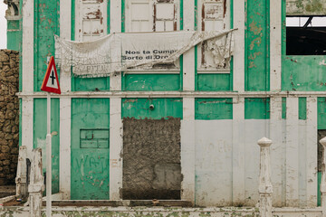 Old building with peeling green paint and weathered textures near a coastal area in an urban setting